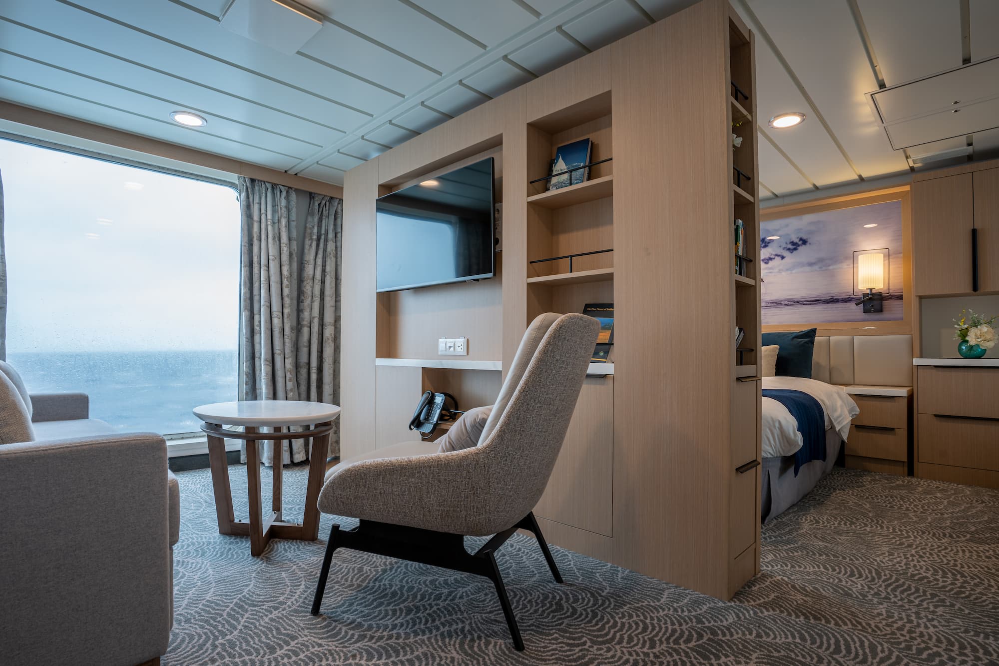 Luxury suite on an Antarctica expedition cruise ship, showing a separate lounge area, large windows and upscale furnishings.