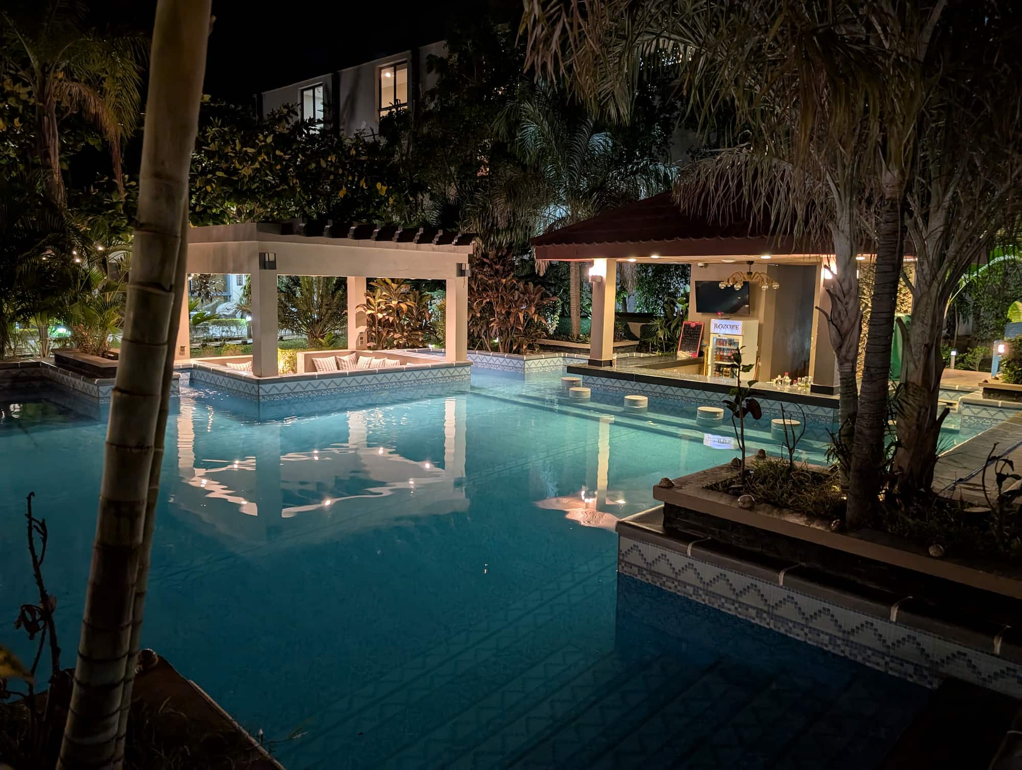 Illuminated swimming pool and poolside bar at the Kozobe Hotel at night, Madagascar.