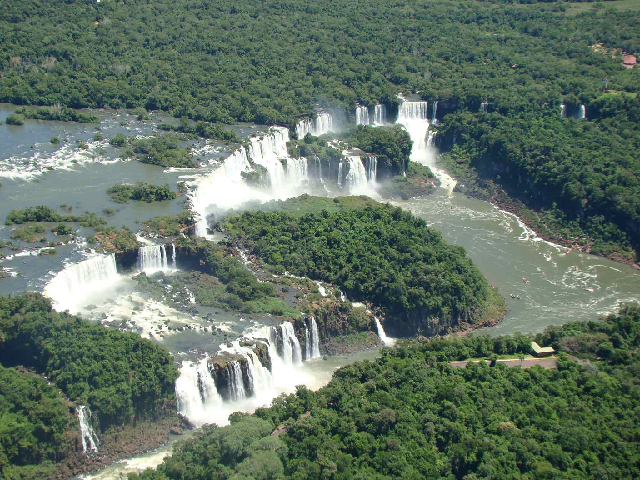 Photo of Iguazú Falls from helicopter showing multiple cascades surrounded by rainforest.