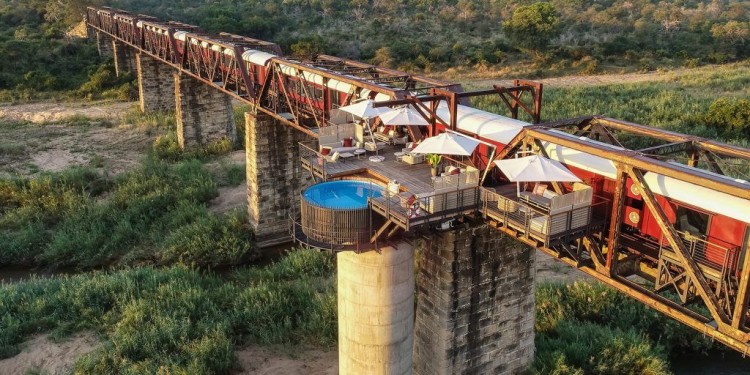 Aerial view of Shalati luxury train lodge on a bridge with a pool and deck in Kruger National Park, South Africa.