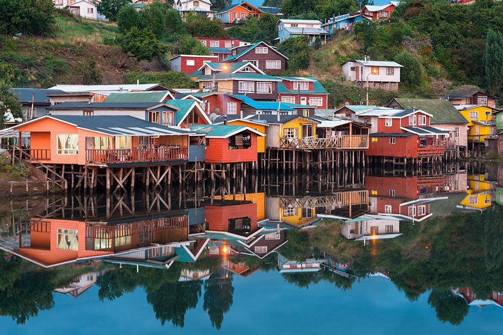 Colourful wooden palafito stilt houses reflected in the water at Castro, Chiloé Island, Chile
