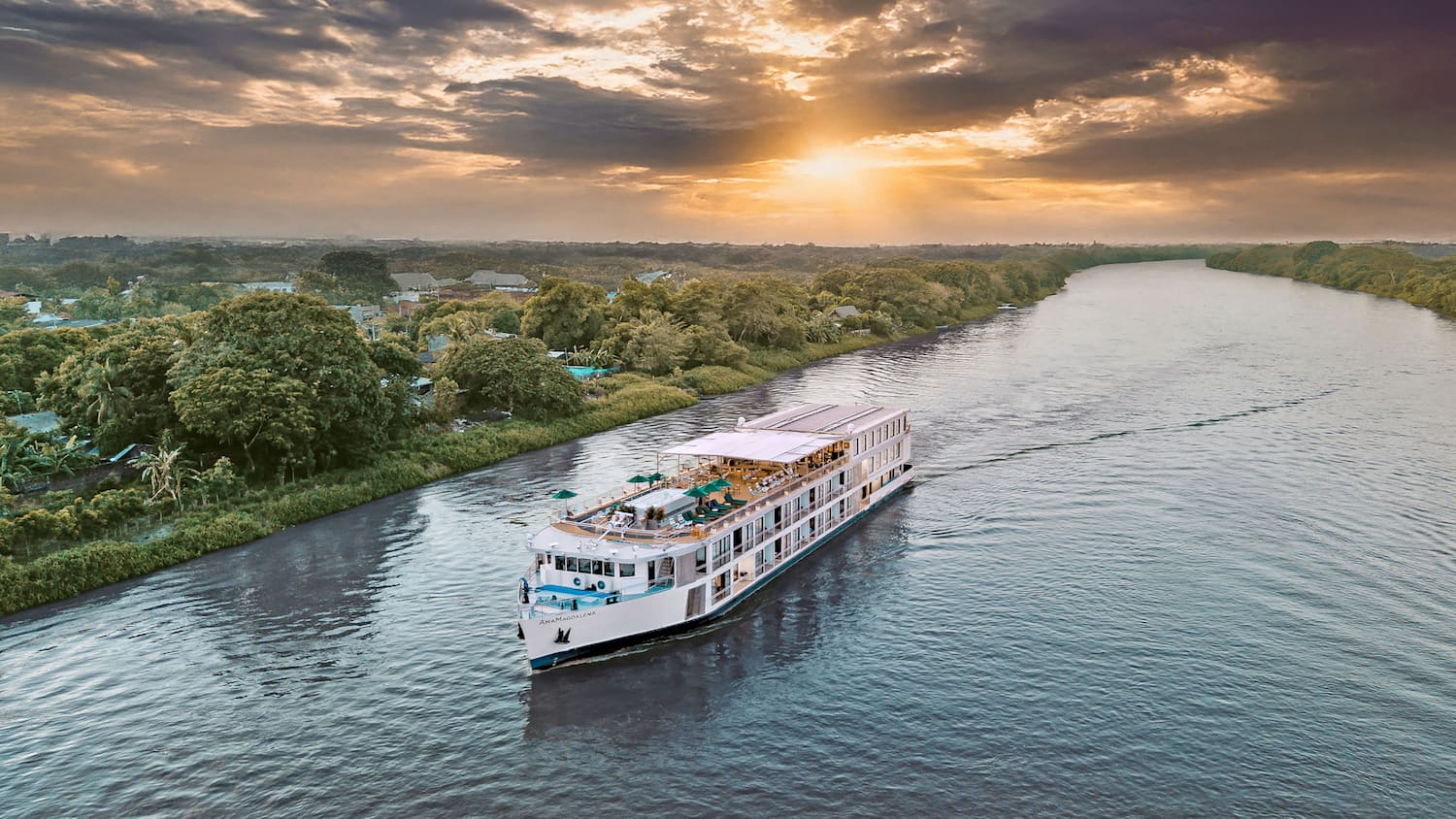 A riverboat sails along Colombia’s Magdalena River with painted houses on the banks.