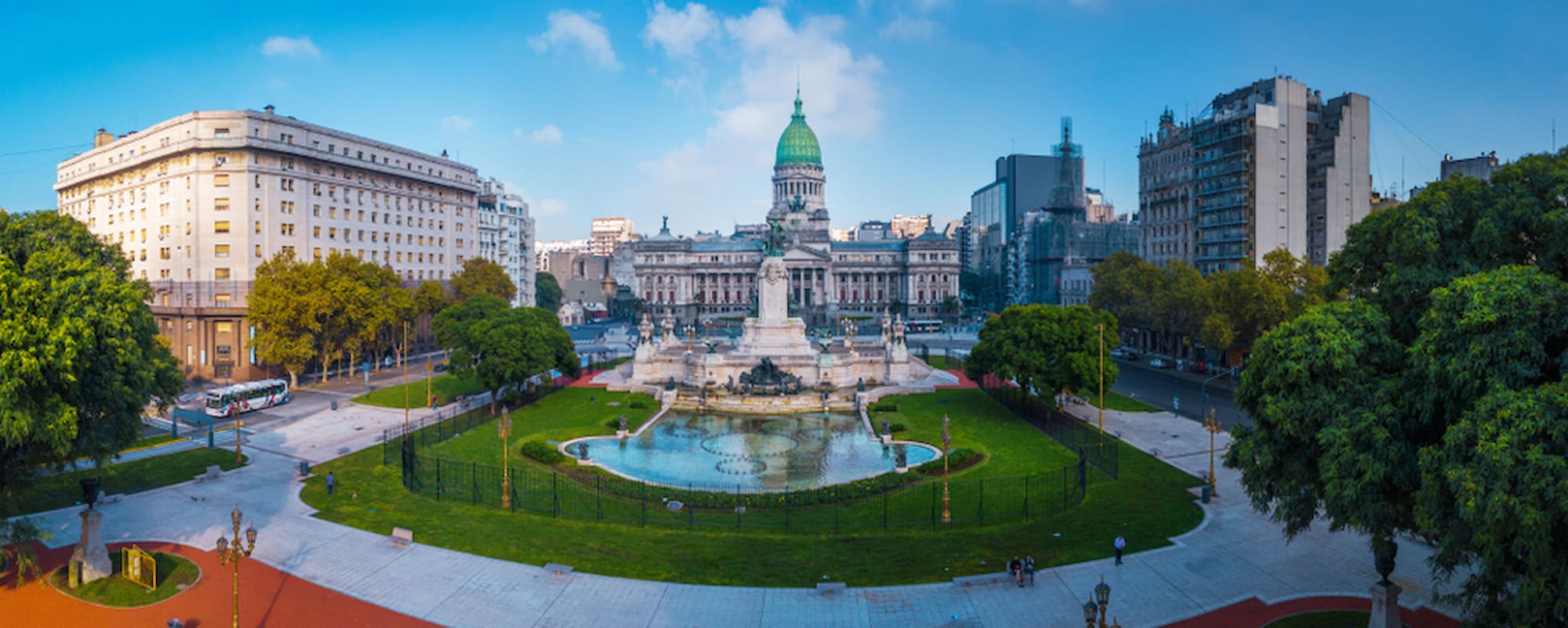 Wide view of Buenos Aires’ National Congress building and surrounding square, with historic architecture, fountains, and tree-lined boulevards..