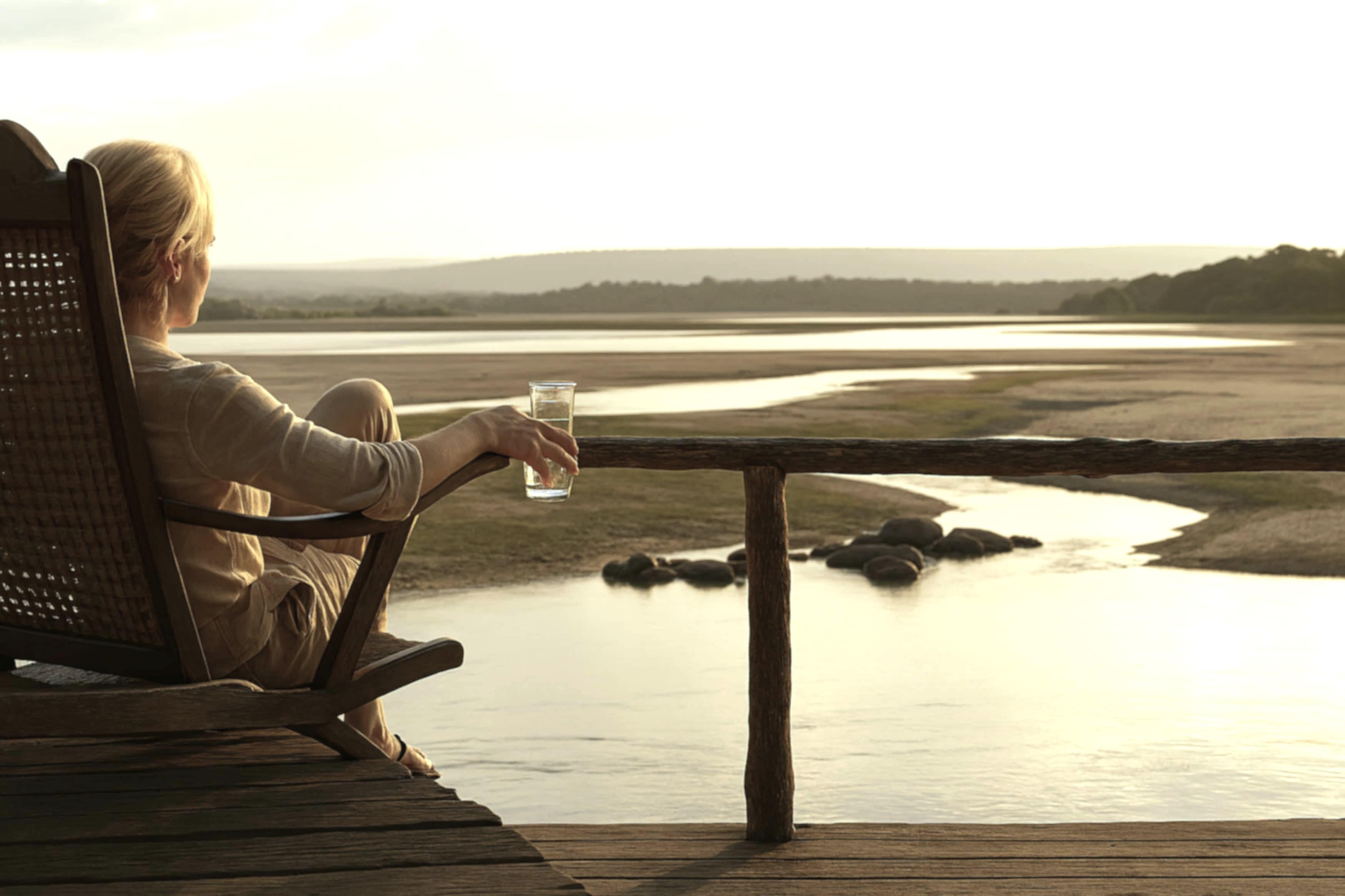 A woman relaxes at the riverside Ruaha Lodge during sunset. A woman relaxes at the riverside Ruaha Lodge during sunset.
