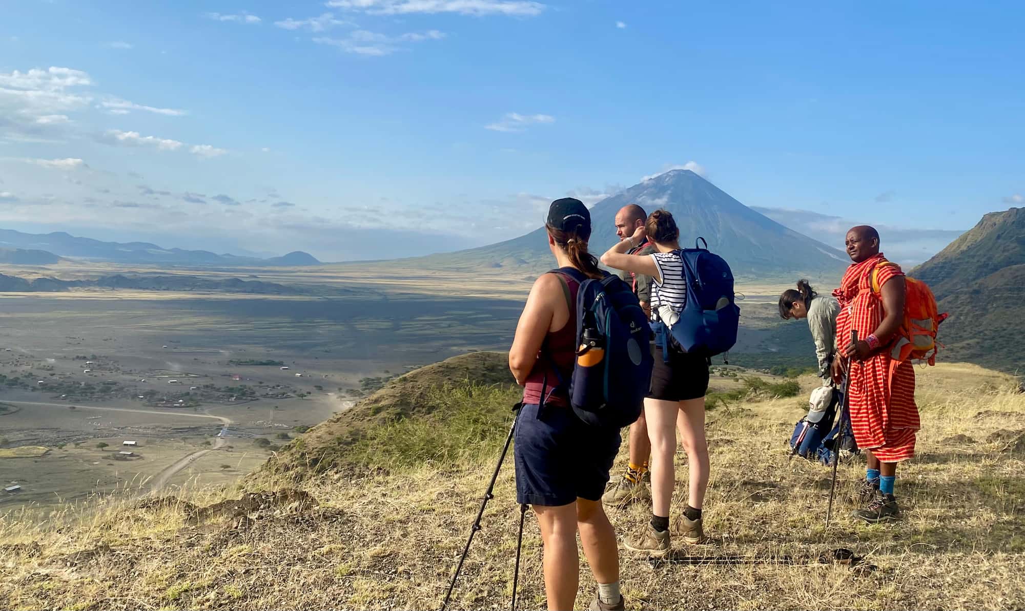 Trekkers pausing on a grassy ridge with mt Kilimanjaro
