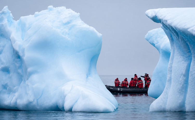 Whale Season tour guest on zodiac in between icebergs