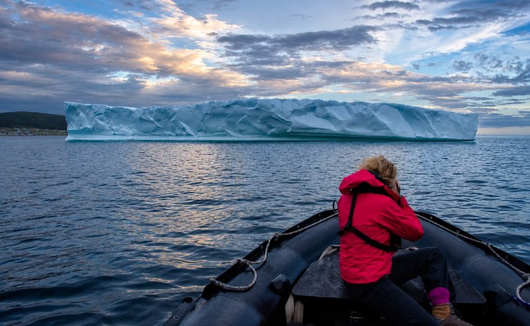 Out of Northwest passage woman taking the massive glacier during zodiac cruise