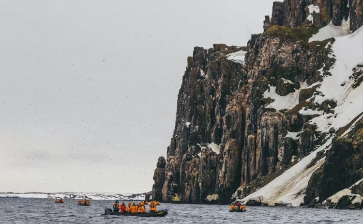 Svalbard in Summer passengers in zodiac get close to bird cliffs