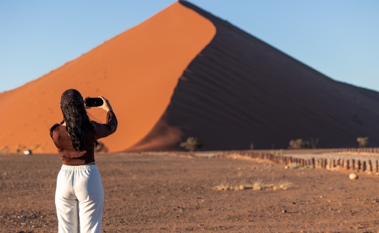 Namibia self drive tour woman standing in front of a towering sand dune in Sossusvlei