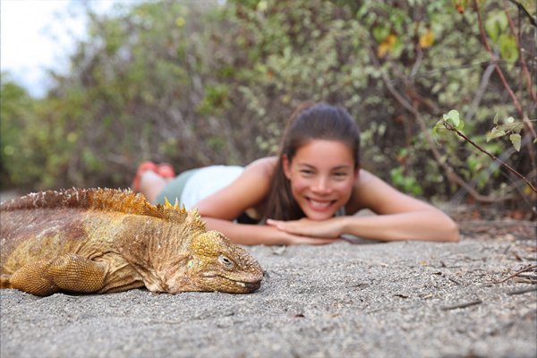 girl watching iguana in Galapagos Islands