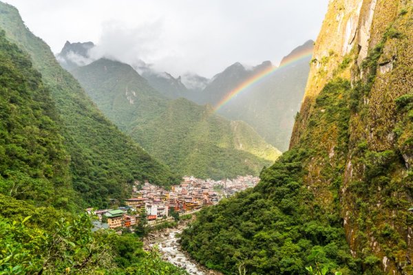 The town of Aguas Calientes under a rainbow, surrounded by steep mountains