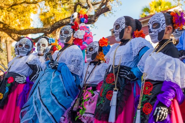 Group of women wearing traditional sugar skull masks and costumes