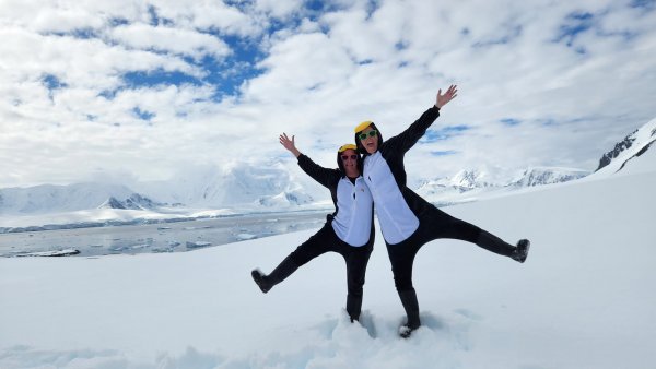 Rach and Tara in penguin onesies, on the ice in Antarctica