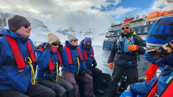 Passengers on a zodiac in Antarctica, wearing matching blue jackets