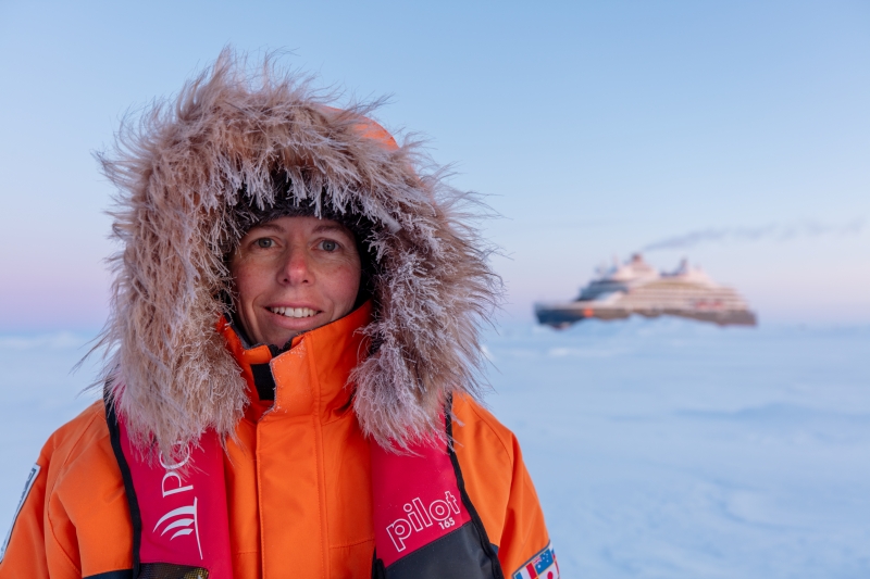 Viva Expeditions team member Tara Sutherland on Arctic ice, with expedition ship in the background. 