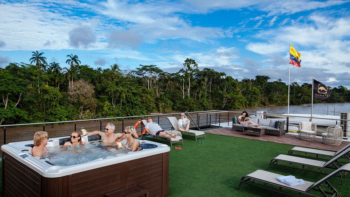 Guests relaxing in a jacuzzi and on the open deck of the Anakonda Amazon river cruise.