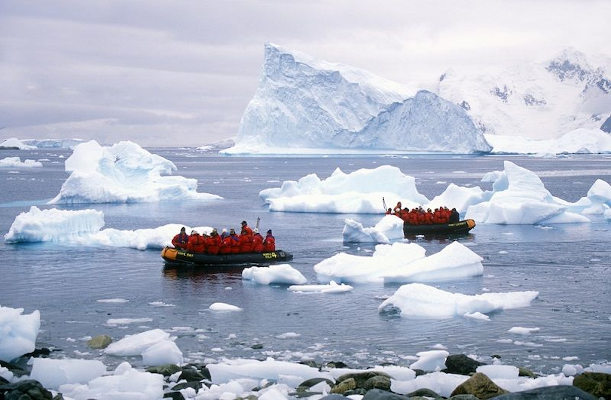 Expedition cruise passengers on Zodiac inflatable boats among icebergs on the Antarctic Peninsula