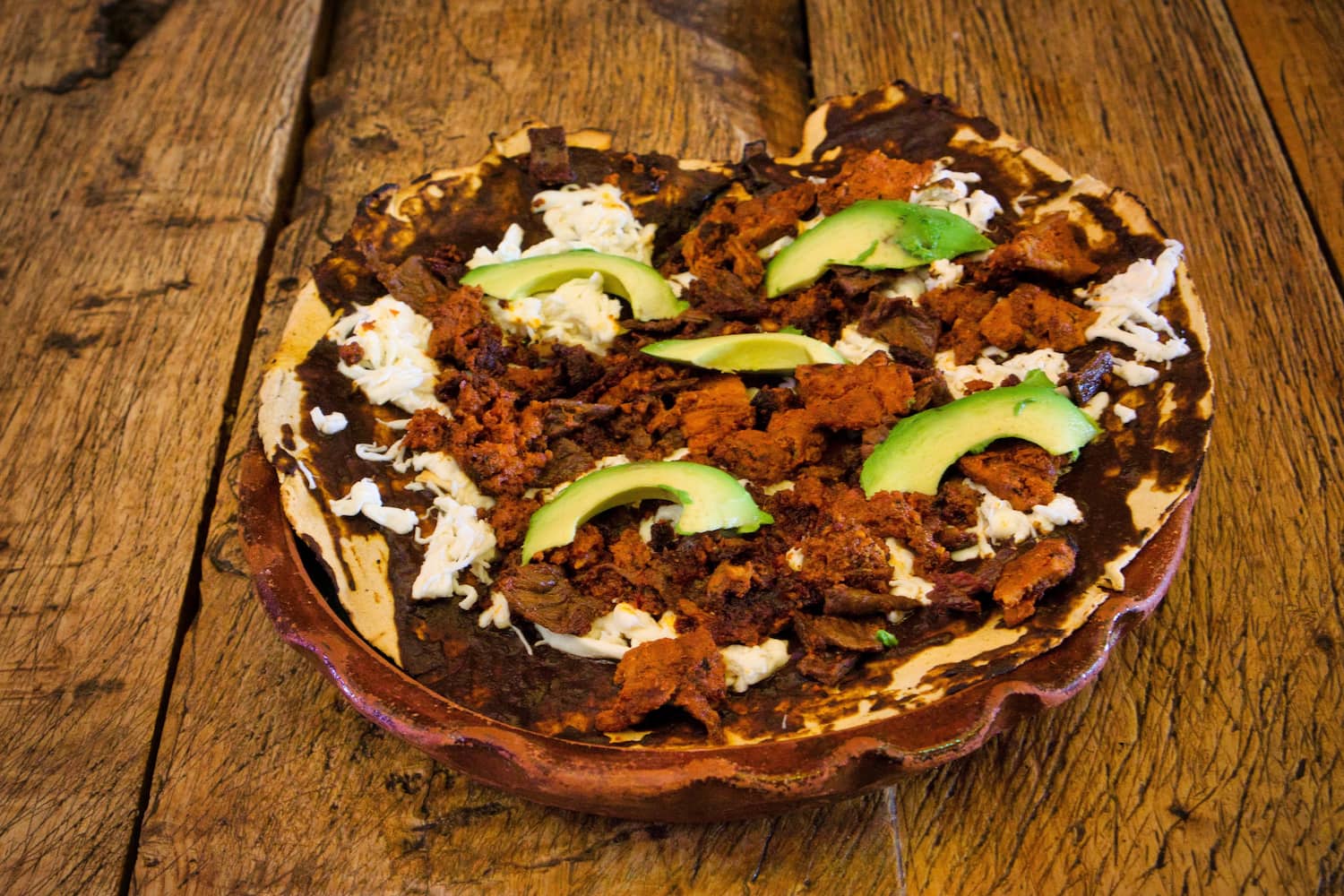 A delicious traditional Oaxacan Tlayuda dish on a wooden table