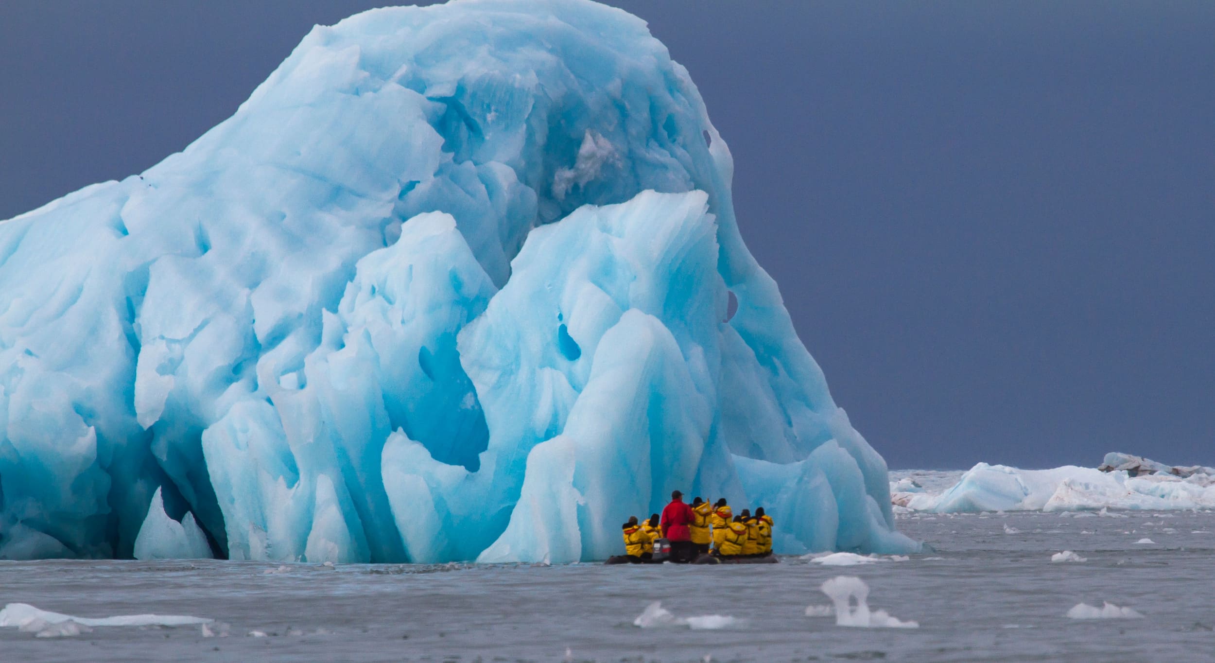 Tourists on a Zodiac cruise in front of a massive glacier.