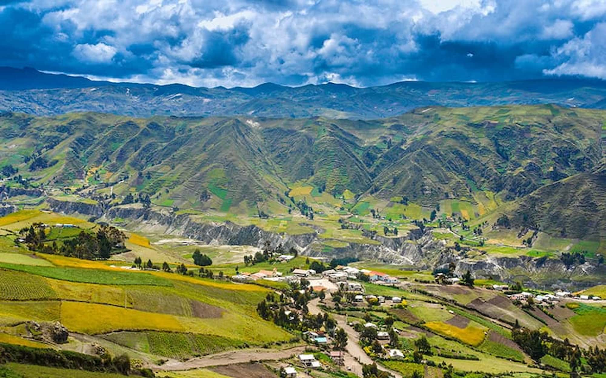 Farming villages and green Andean valleys under a dramatic cloud-filled sky..
