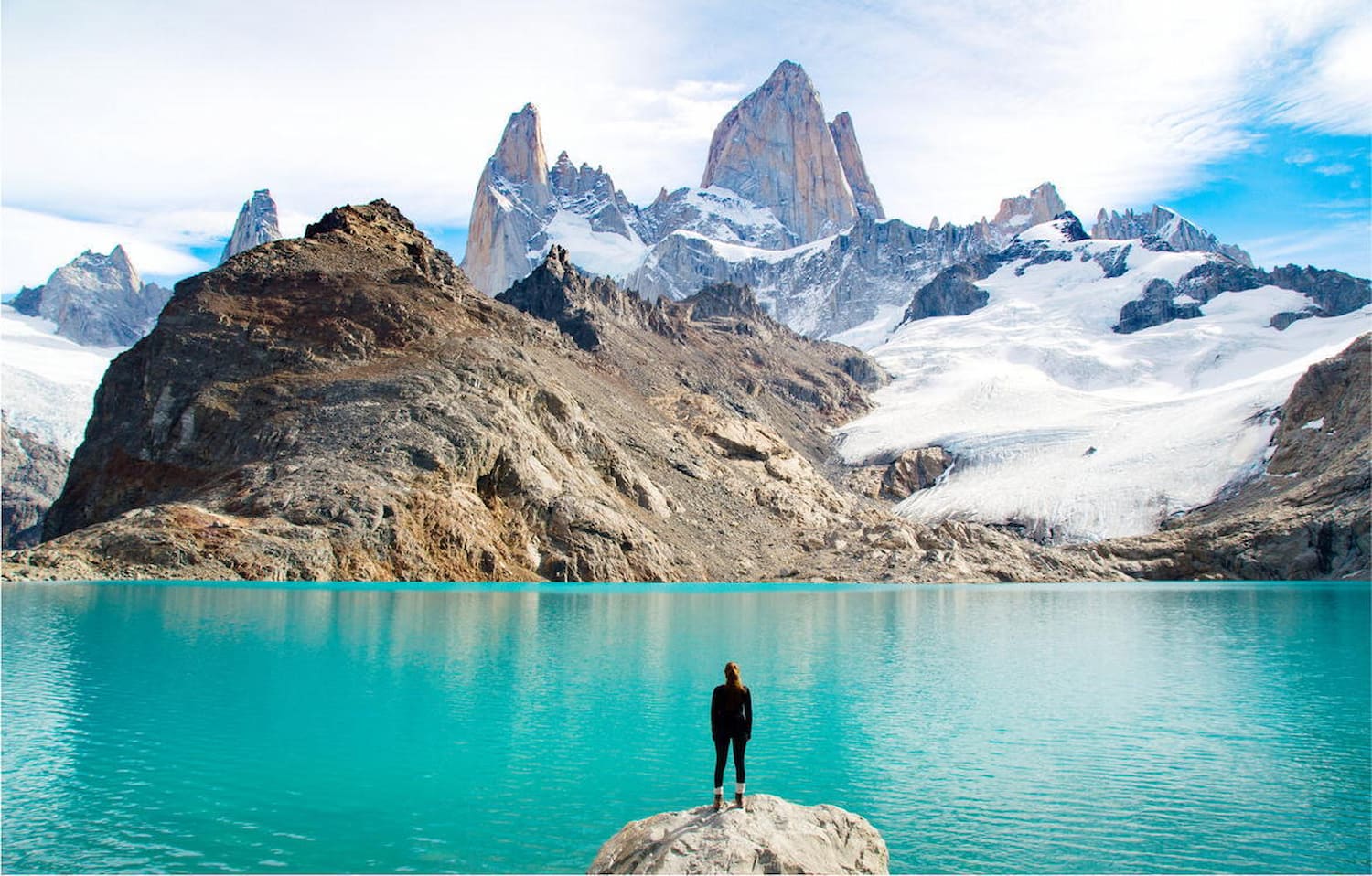 Hiker overlooking the turquoise lagoon and glacier at Mount Fitz Roy in Patagonia during summer.