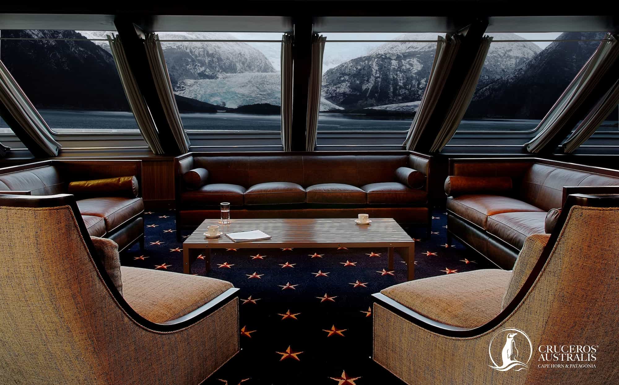 Observation lounge with leather sofas and panoramic windows overlooking a glacier, aboard an Australis expedition ship, Chilean Patagonia.