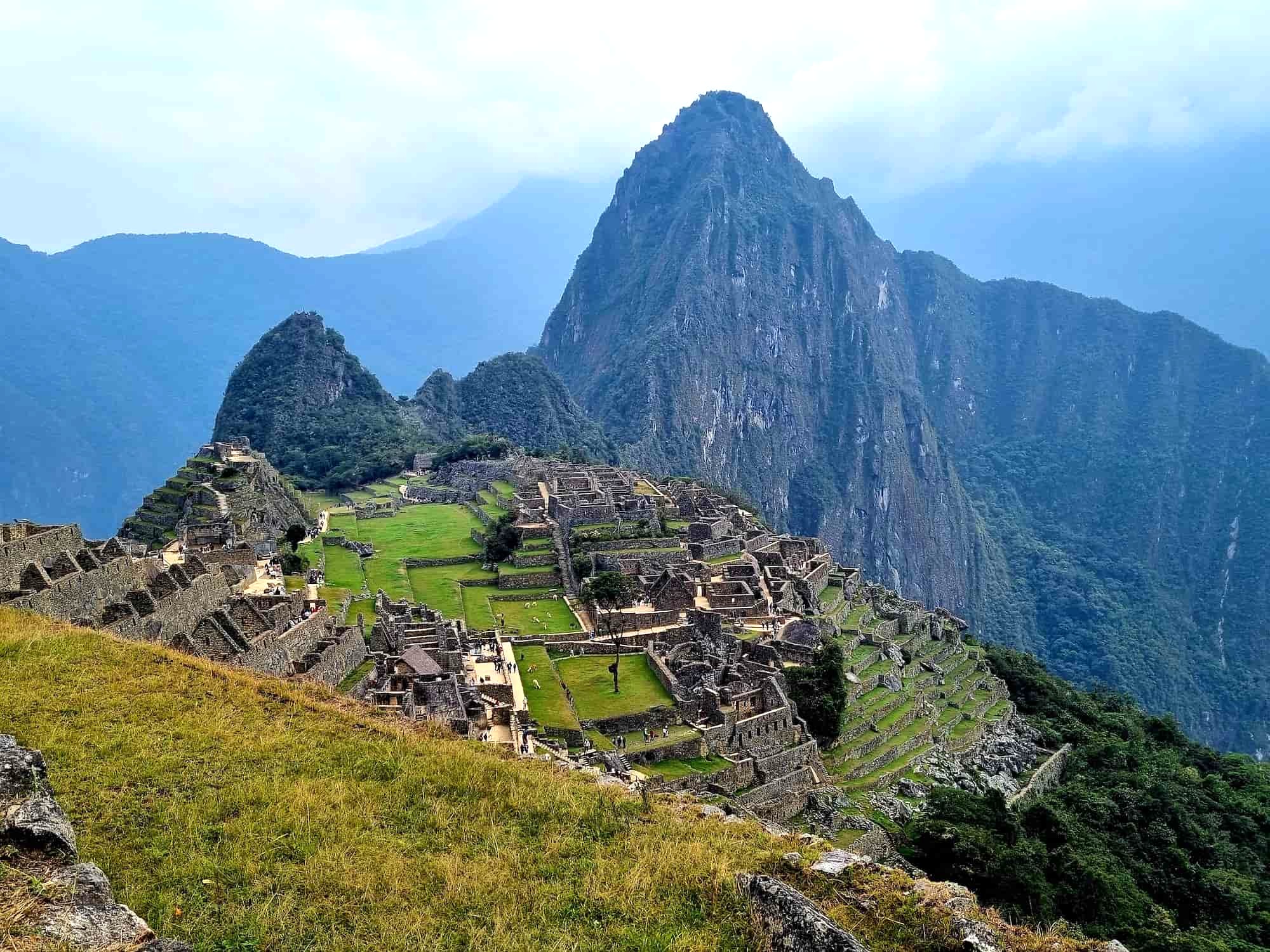 Machu Picchu ruins and surrounding Andes mountains on a sunny day, Peru, showing the classic postcard view. Machu Picchu ruins and surrounding Andes mountains on a sunny day, Peru, showing the classic postcard view.