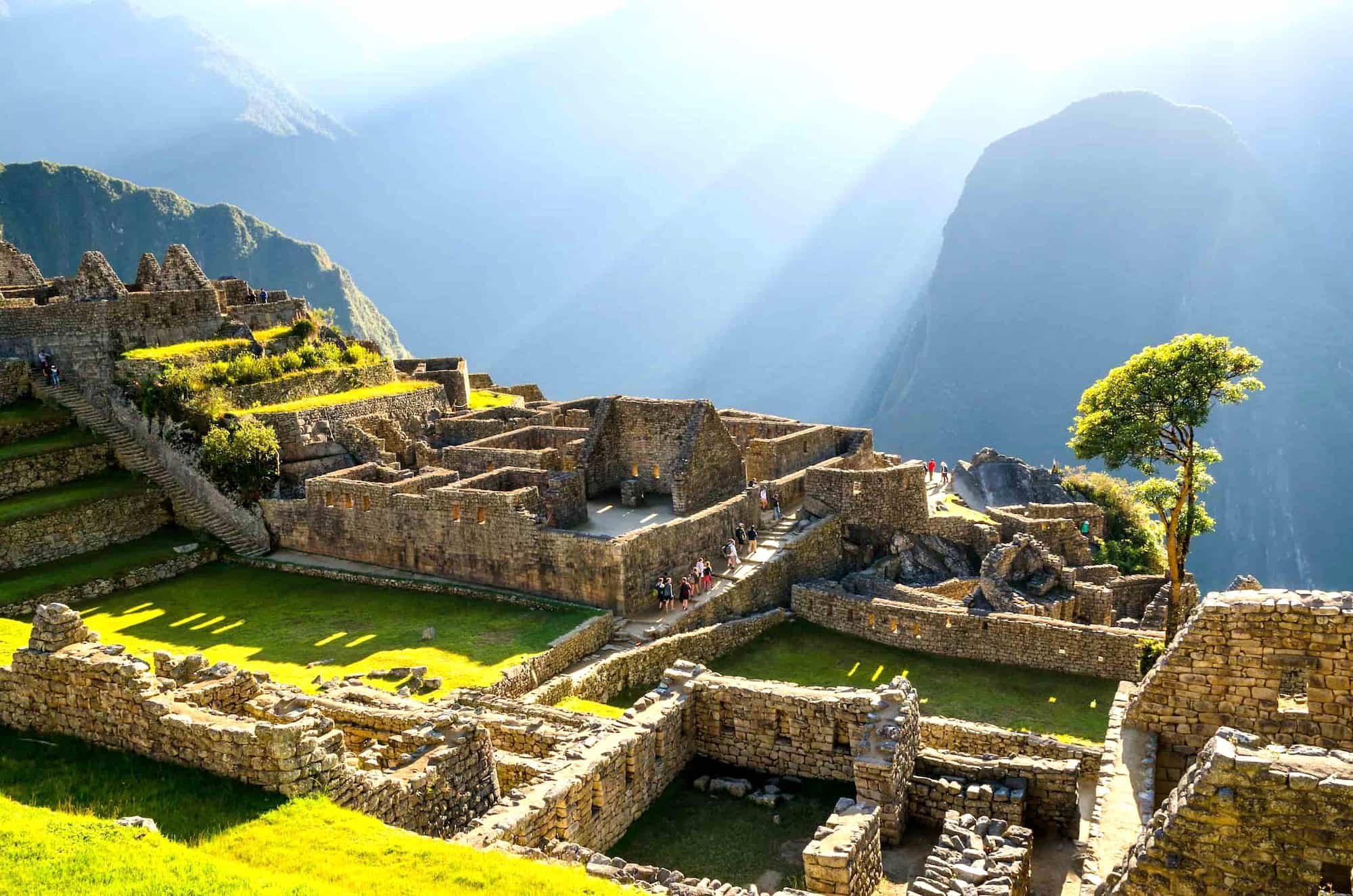 View of Machu Picchu terraces and stone structures in the Andes, Peru, with visitors exploring the site. View of Machu Picchu terraces and stone structures in the Andes, Peru, with visitors exploring the site.