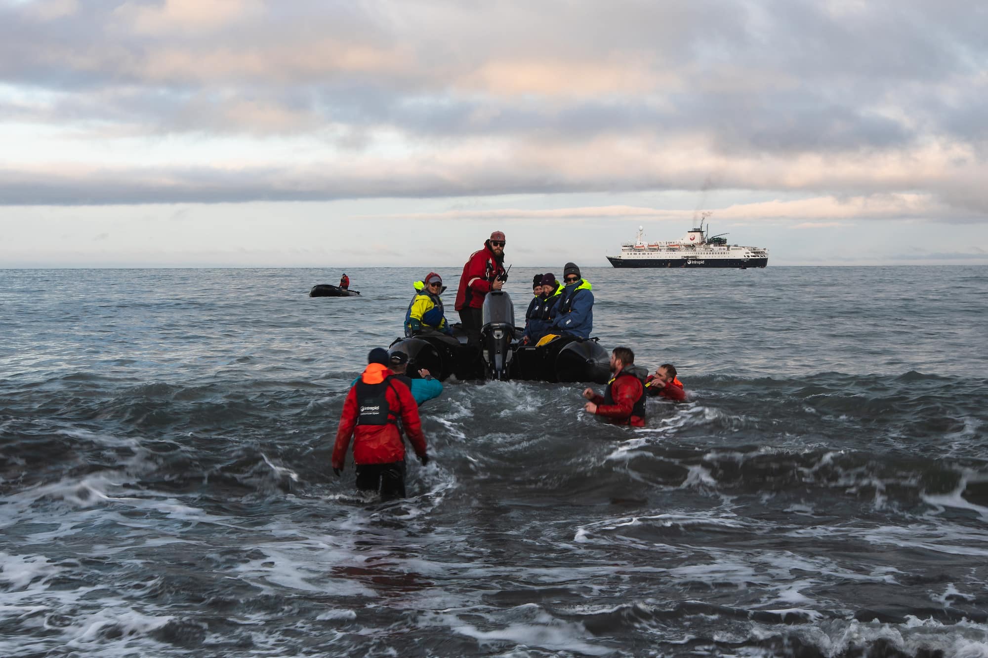 Polar expedition cruise crew getting ready to disembark passengers from a Zodiac in rough seas.