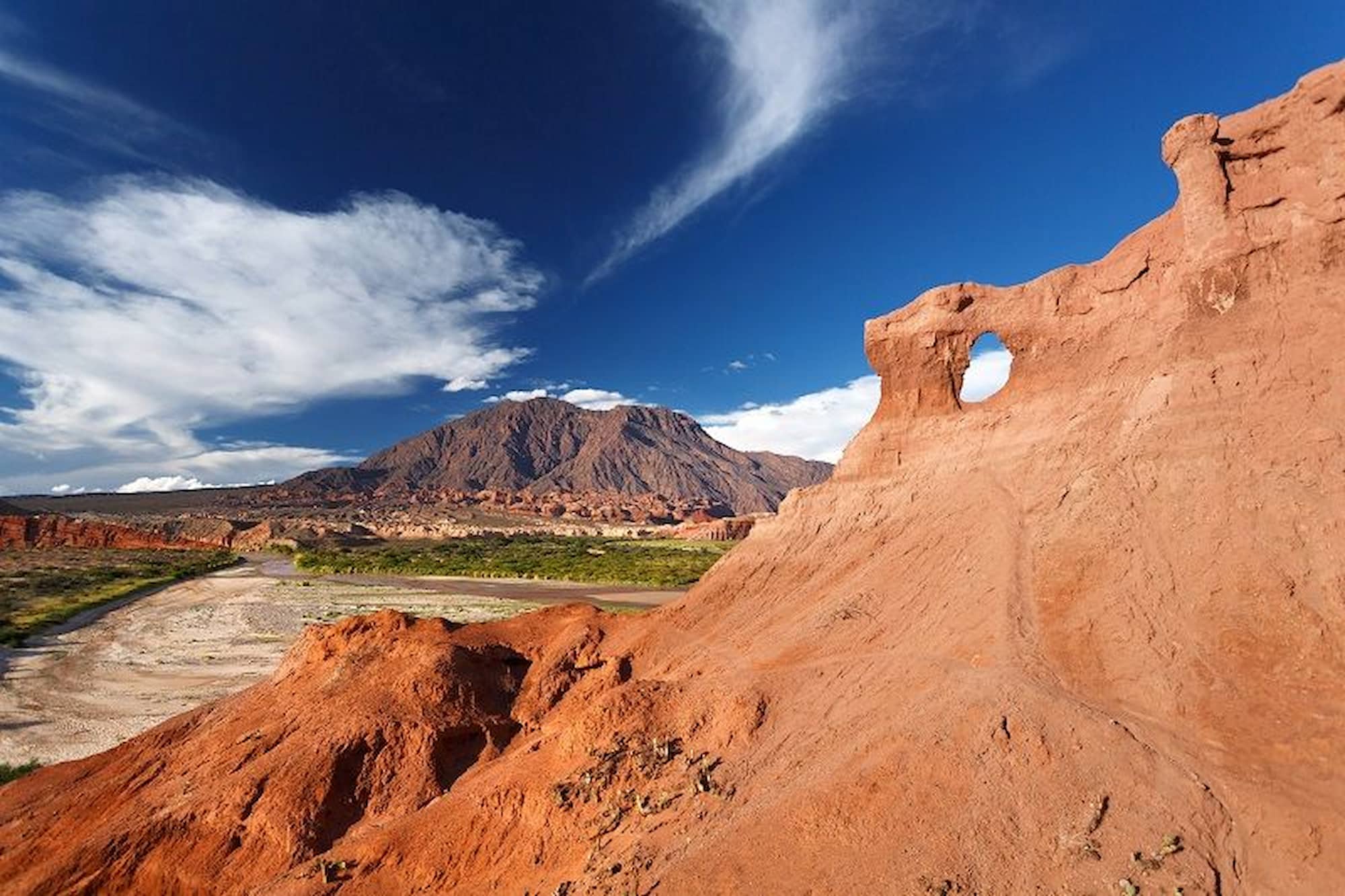 Village street in Purmamarca with red mountains of the Quebrada de Humahuaca in the background.