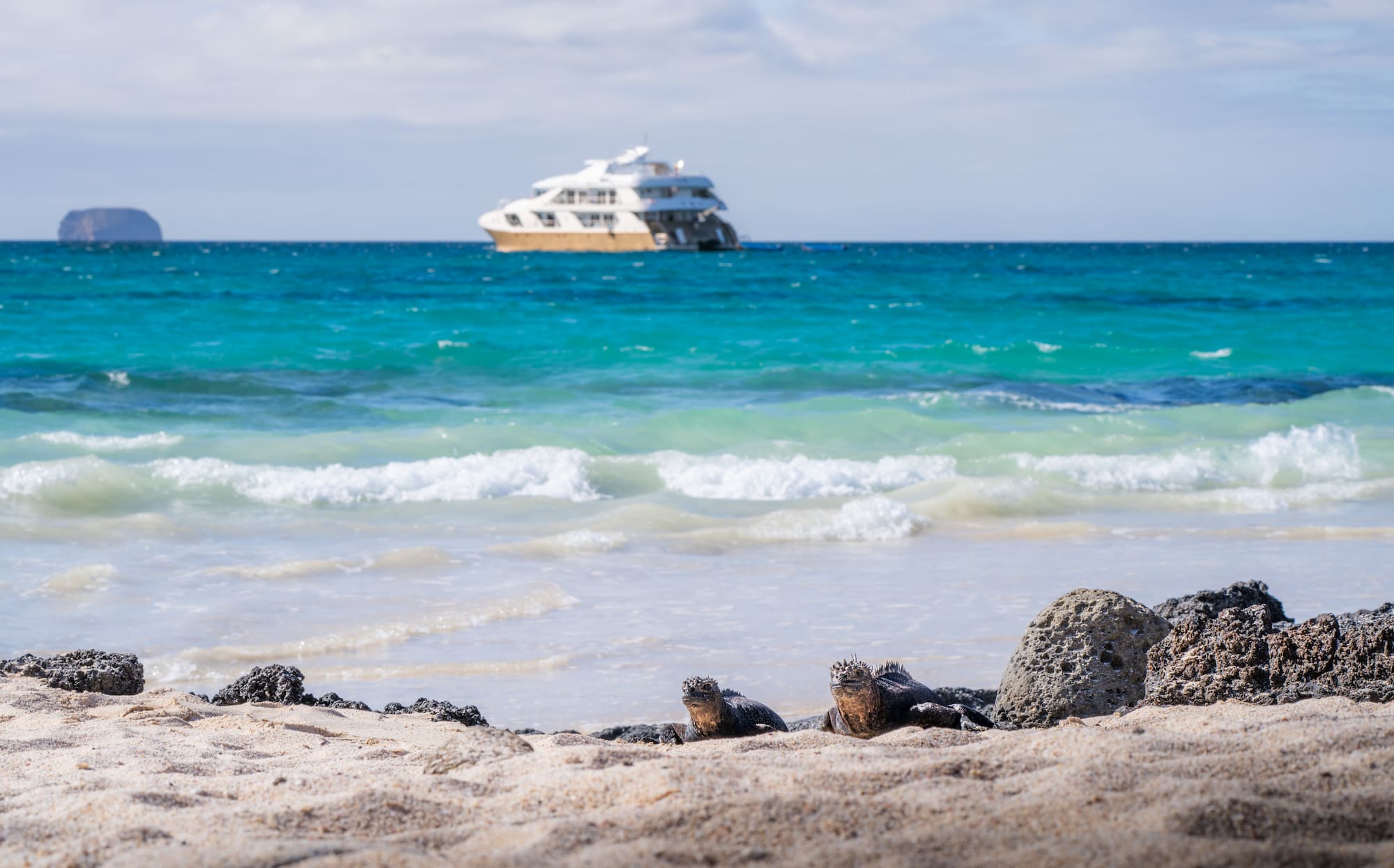 Small expedition catamaran anchored off a volcanic island, Galapagos Islands, Ecuador.
