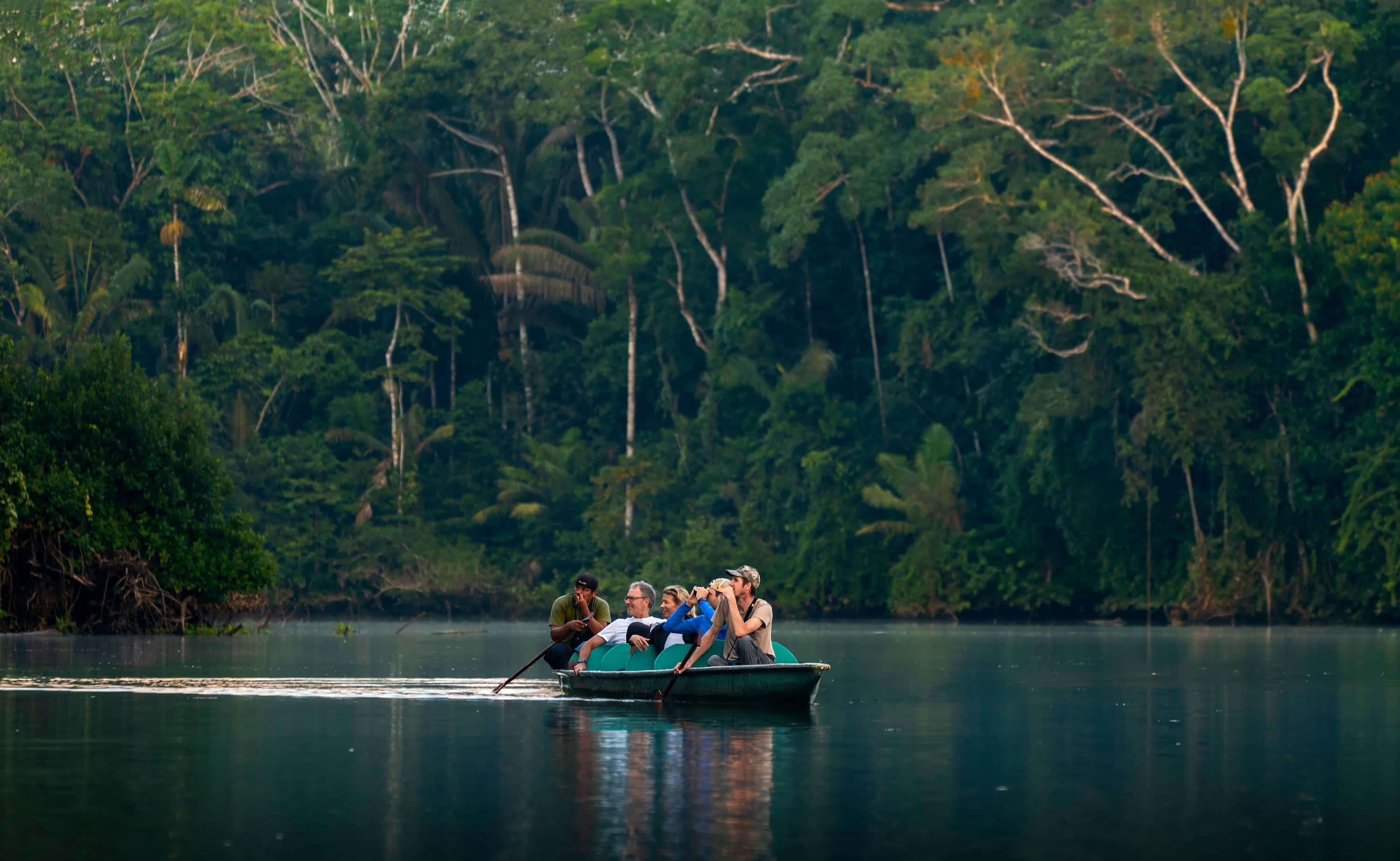 Small boat exploring a tropical river during the high water season in the Amazon rainforest.