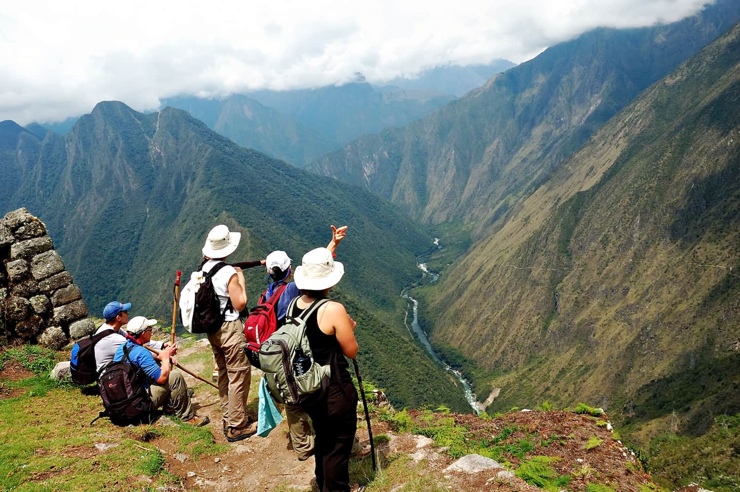 Hikers overlooking a deep Andean valley with a winding river below.