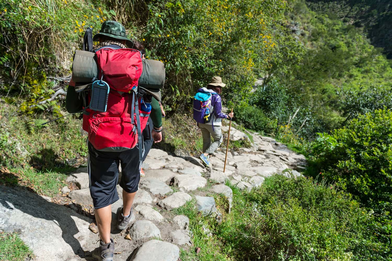 Two hikers walking down cobbled stone steps on an Inca Trail section in the Andes during dry season.